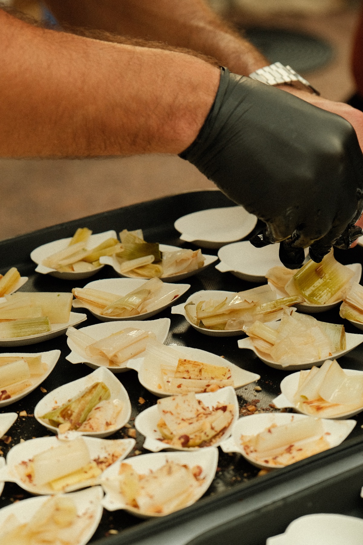 Main gantée dressant des endives garnies en canapés